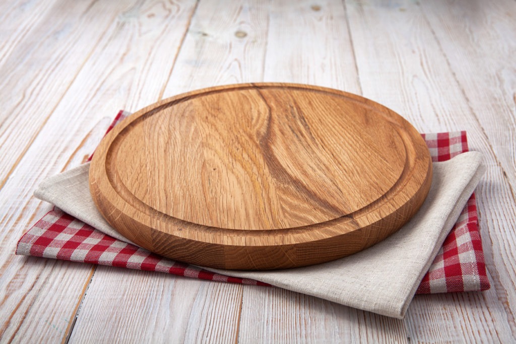 Pizza board with a napkin on white wooden table