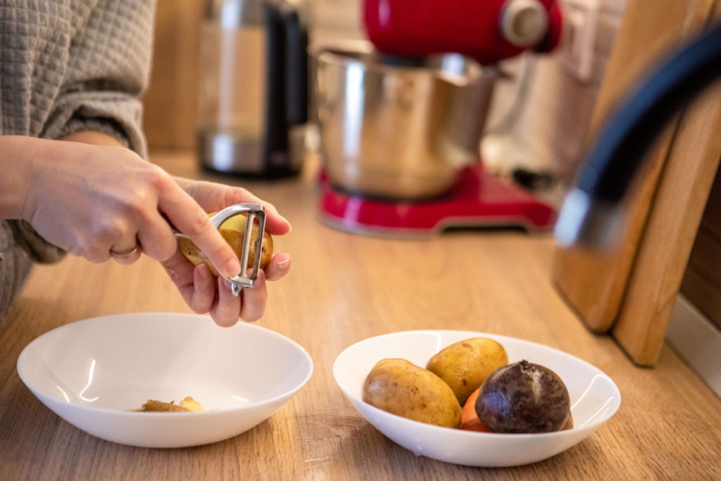 Woman peeling a potato using a peeler