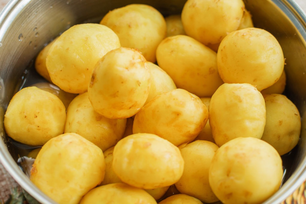 Fresh peeled small potatoes are in a saucepan