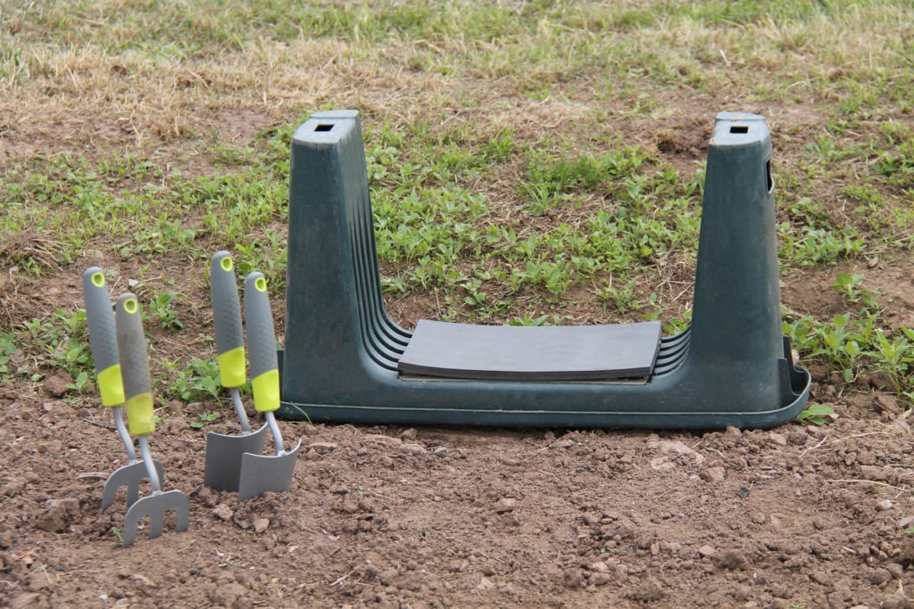 garden kneeler, trowels and forks in a garden