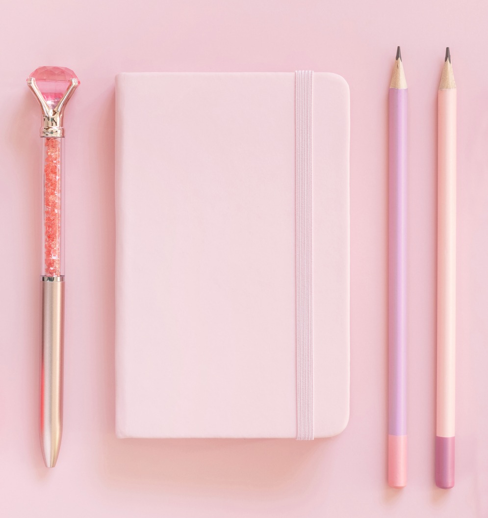 pink notebook, pink pencil and pink pen with gemstone in a light pink background