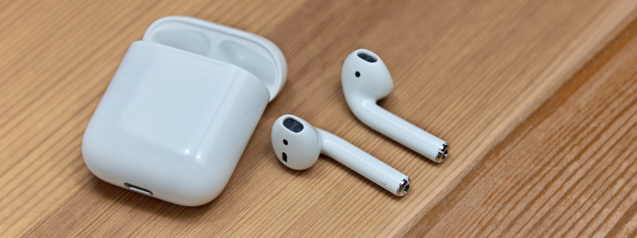 white wireless earphones with charger box in a wooden background
