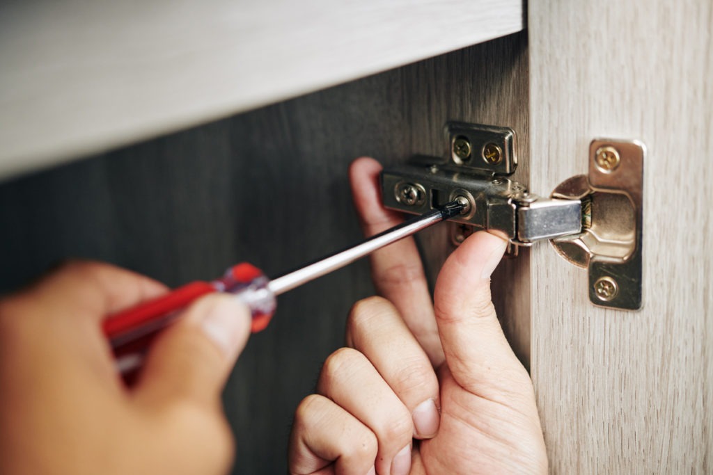 Man screwing a door hinge.