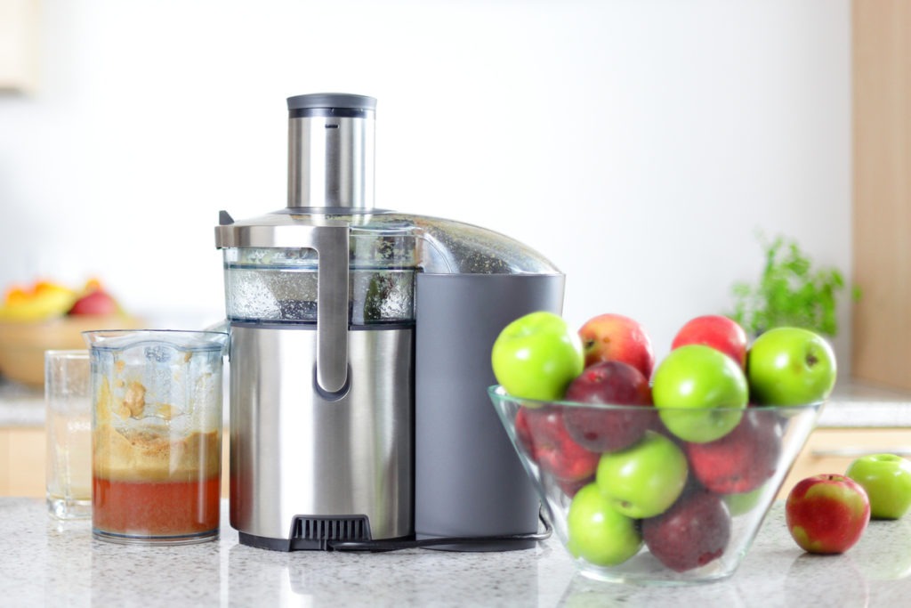 a centrifugal juicer along with a bowl of fresh apples