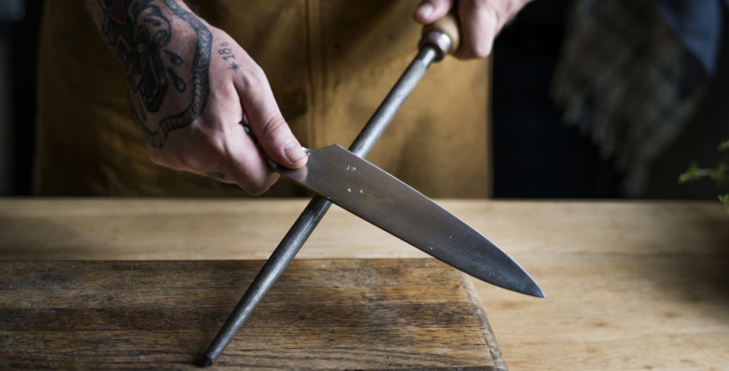 man sharpening the blade of a kitchen knife