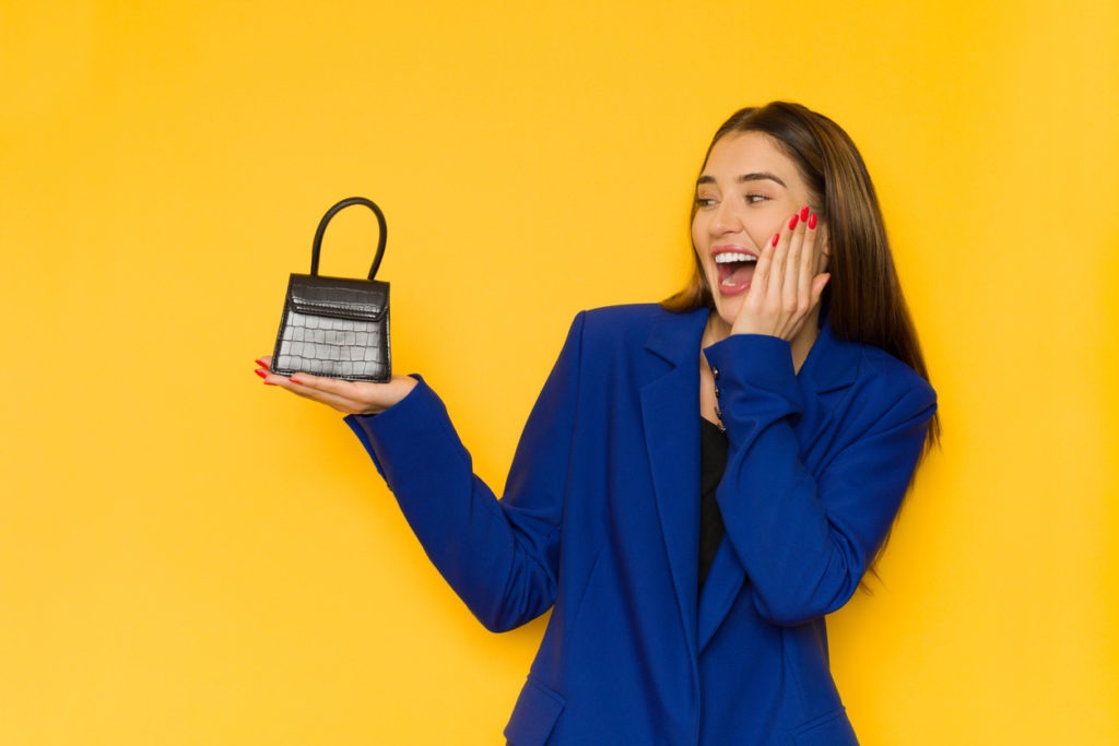 woman wearing a blue blazer holding a small black bag