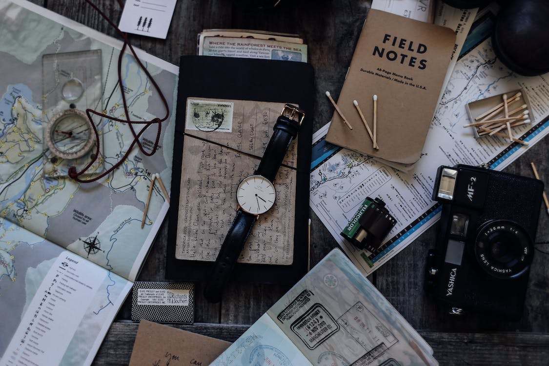 A set of different personal travel items and accessories on a wooden surface