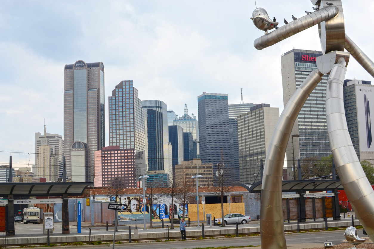 "The Traveling Man" robot statue in Deep Ellum with view of downtown Dallas skyscrapers