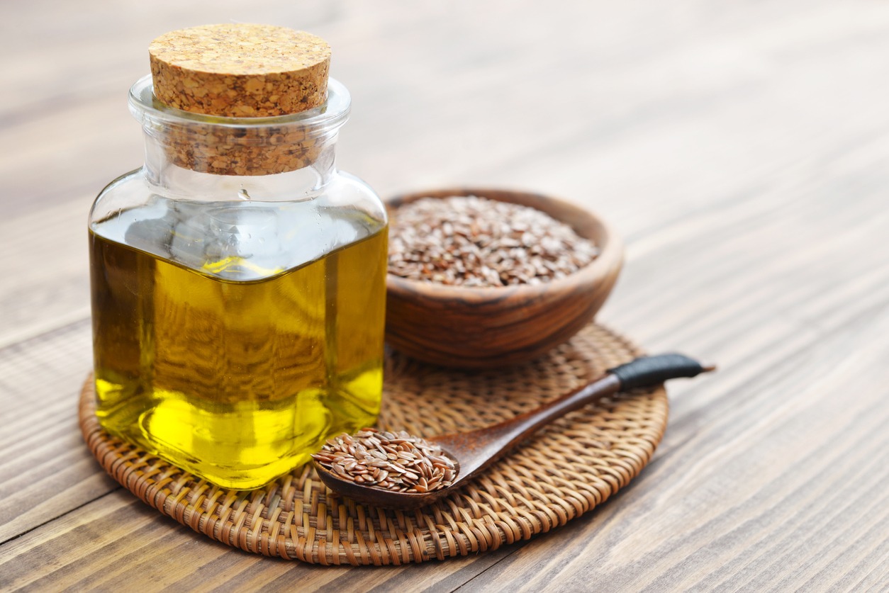 Flaxseeds and a bottle of oil on a table.
