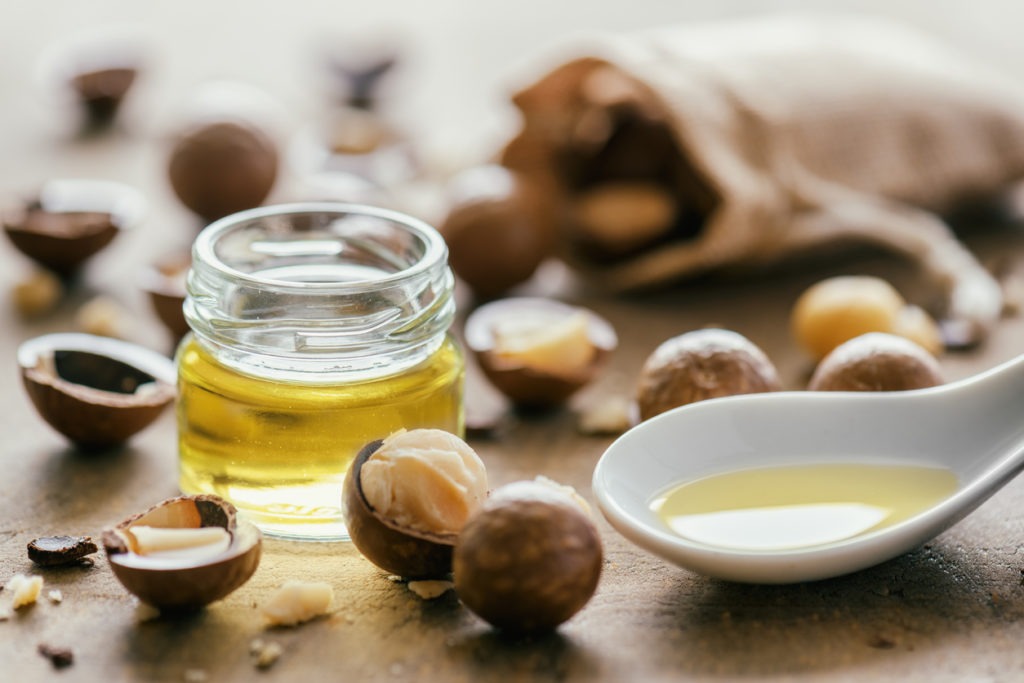 Macadamia nuts and natural macadamia oil in close-up on a wooden board 