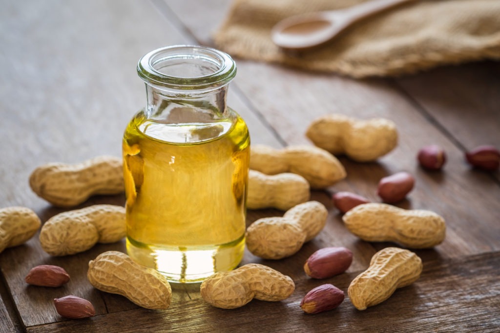 Peanuts on a wooden table with peanut oil in a glass bottle 