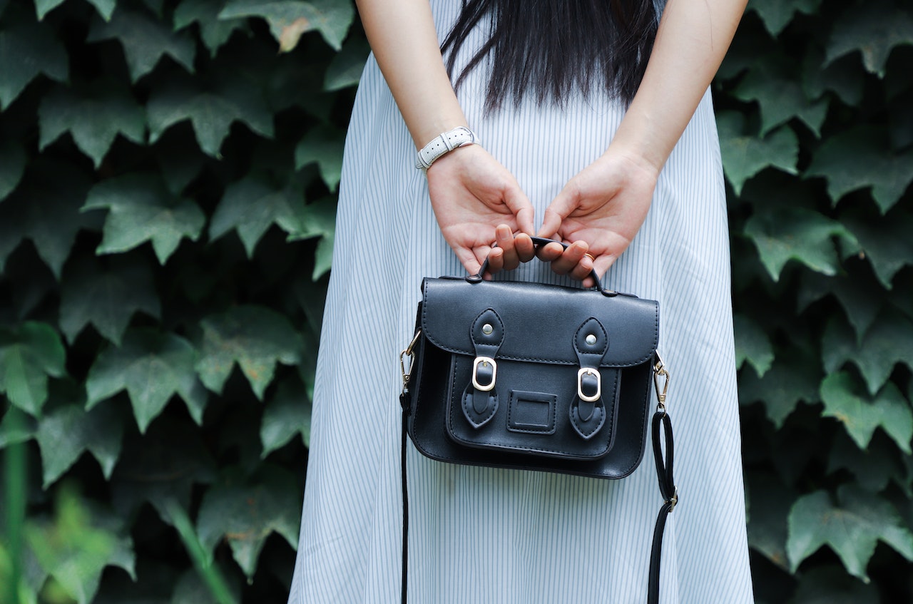 a woman in a dress holding a black handbag