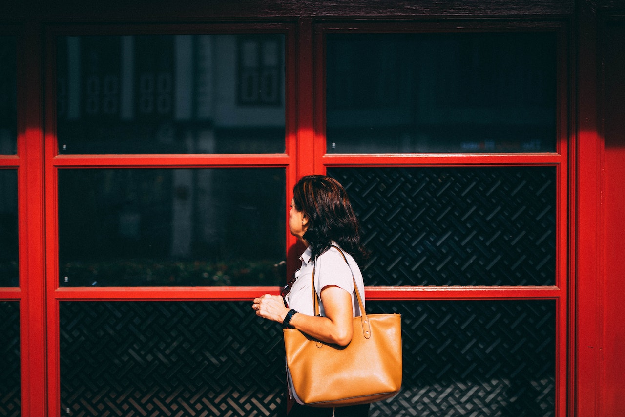 a woman in front of an establishment carrying a handbag on her shoulder