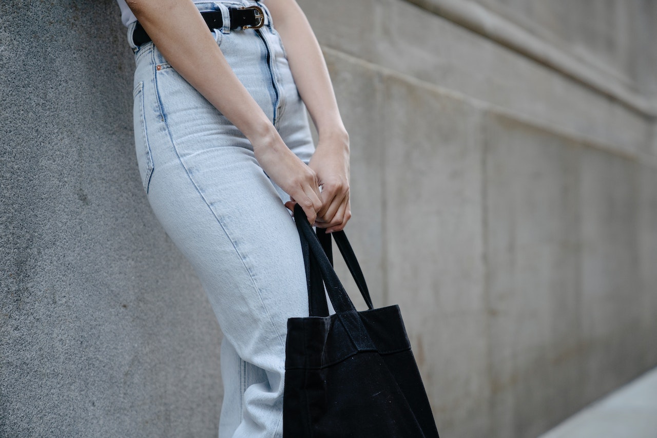 the lower half of a woman carrying a bag in front of her