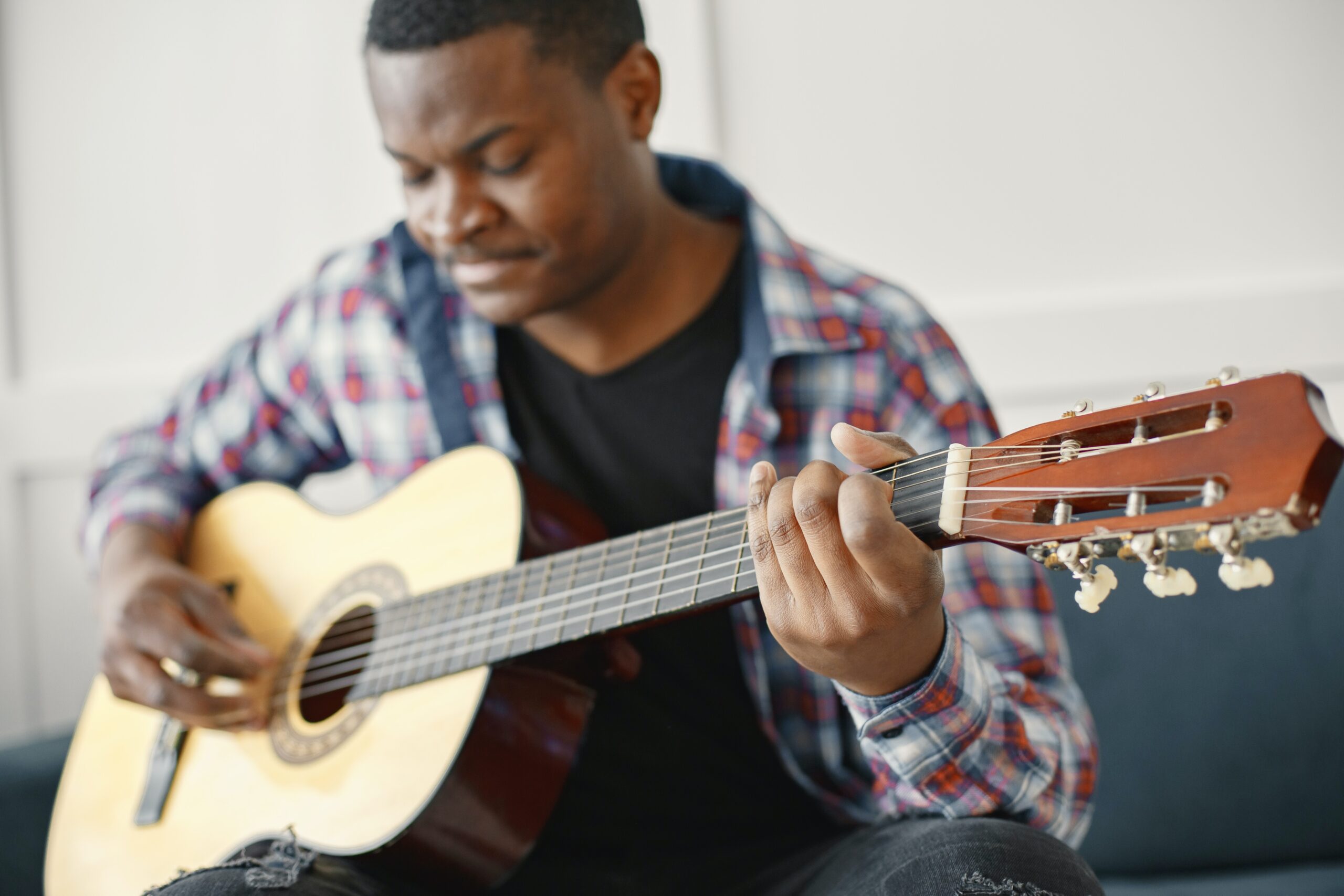 man playing the guitar wearing one-shoulder dress inside a room