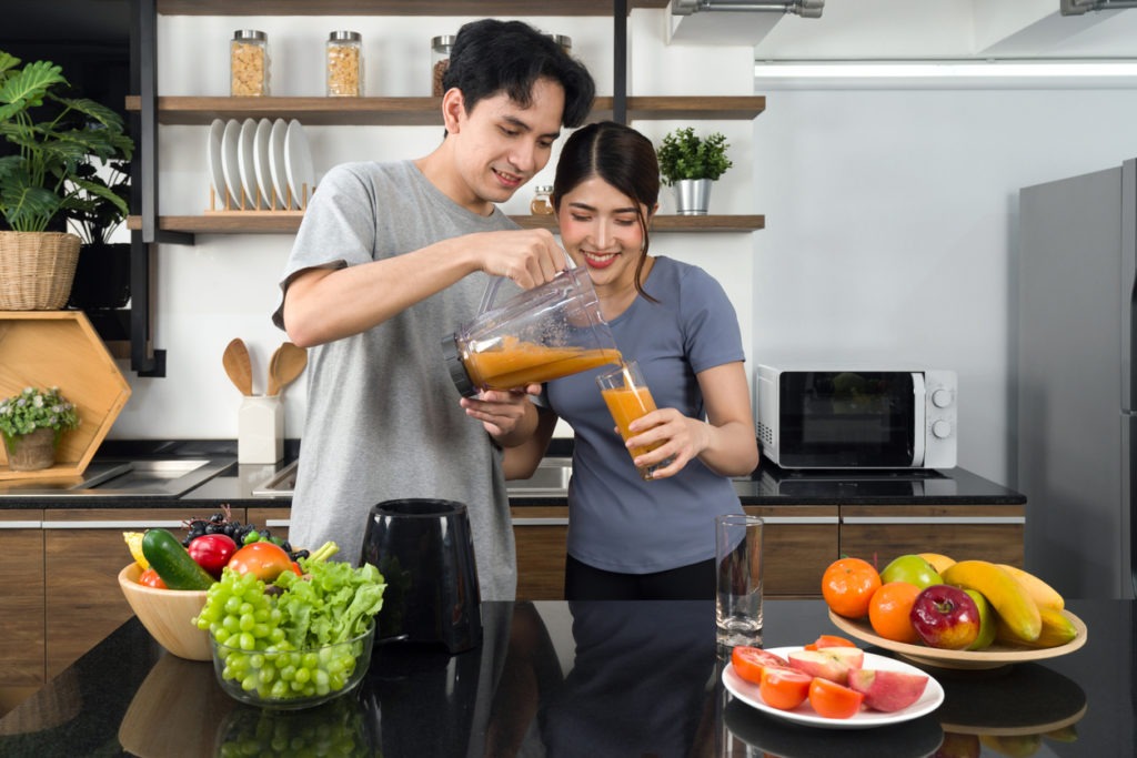 A man putting vegetables on a glass blender jar