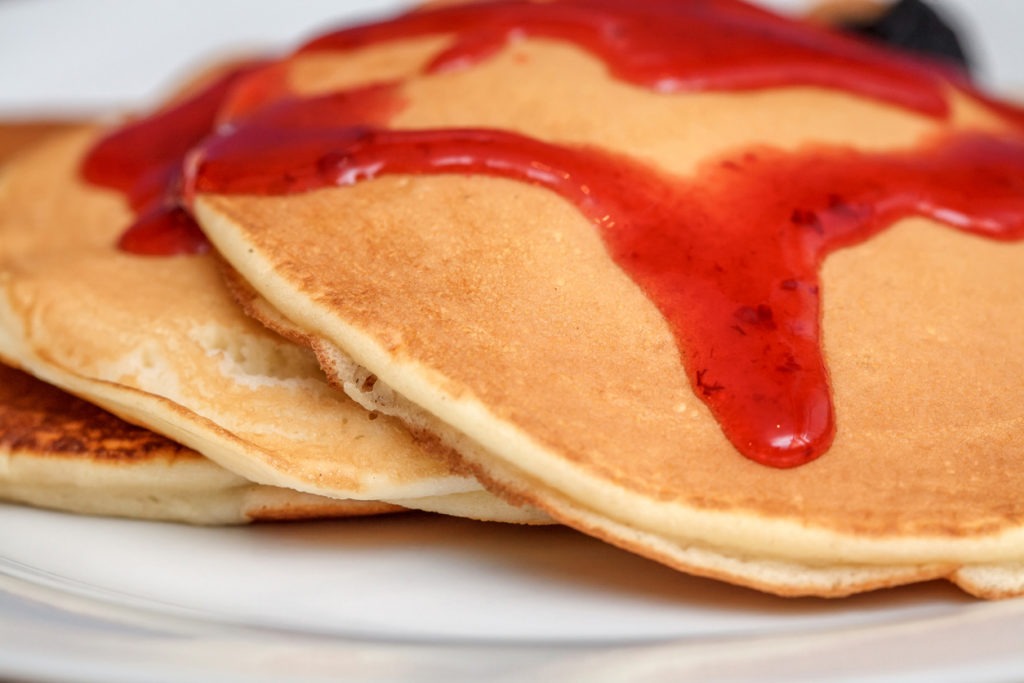Delicious pancakes with red sweet strawberry syrup