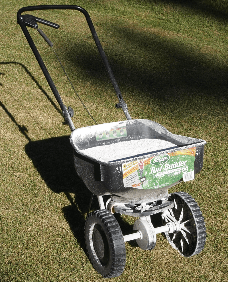 A hand pushed rotary spreader with a load of fertilizer