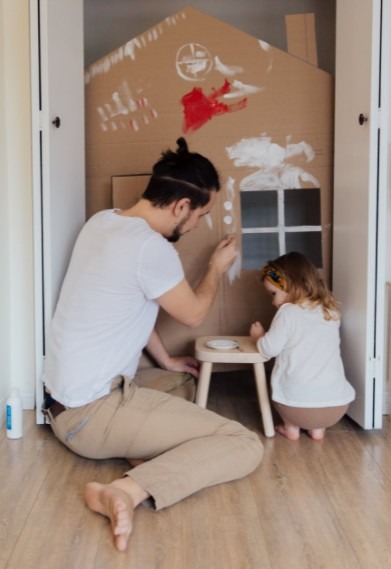 Man in White Shirt and Brown Pants Painting Cardboard House