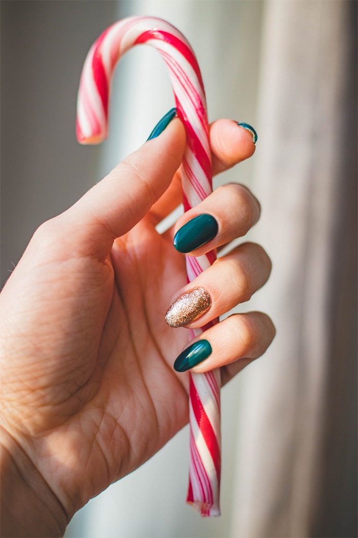 A woman with nail polish holding a candy cane