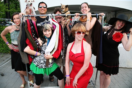 A group of people posing around a clothes rack