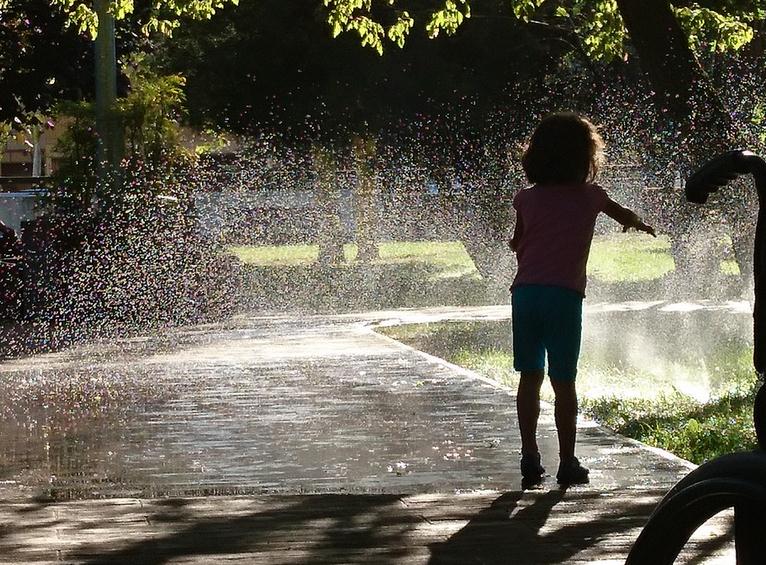 girl playing with the water sprinklers