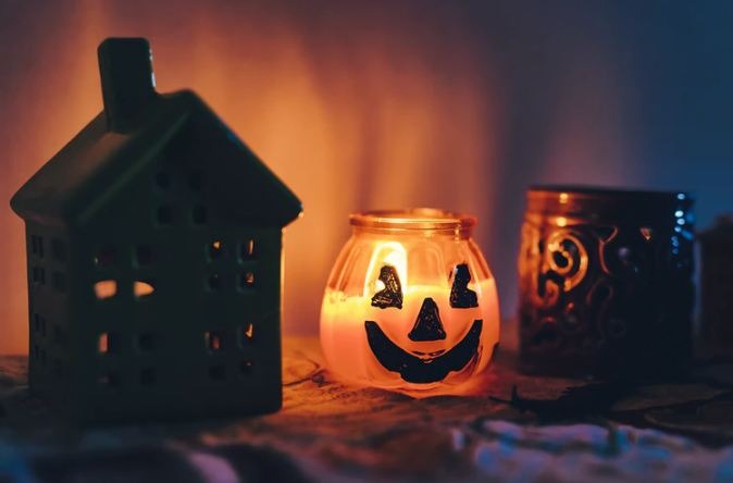 a Halloween candle next to candle holders on a bench