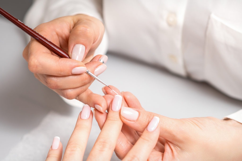 Manicurist drawing nail with thin brush