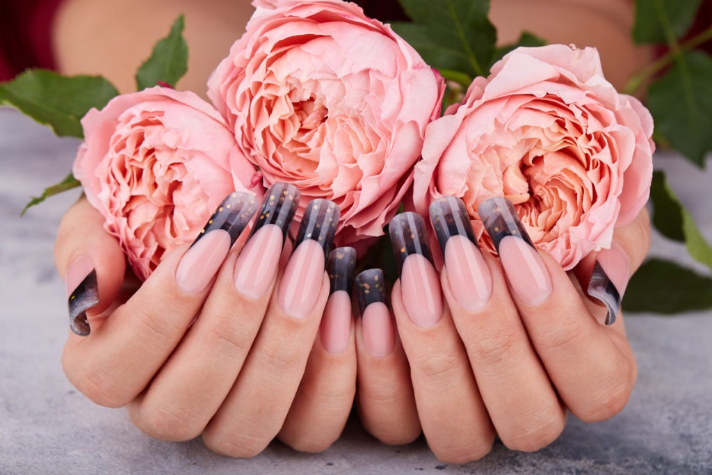 Woman’s nails painted with black and pink polish, pink flames, and pink ribbon