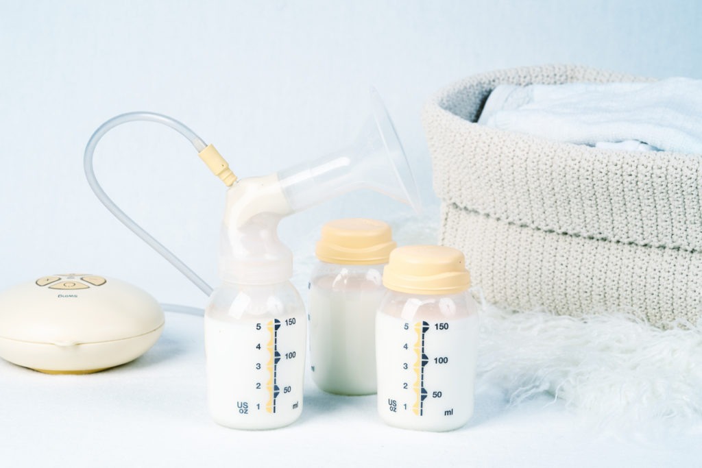  breast pump and stash of milk, baby clothing in the background
