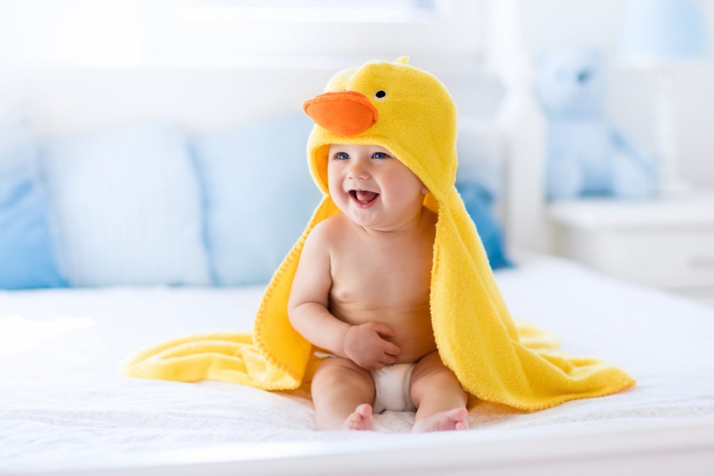 giggling baby in a yellow hooded towel