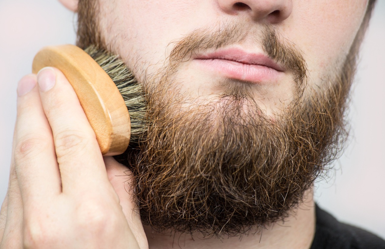 Close up of a man using a beard brush