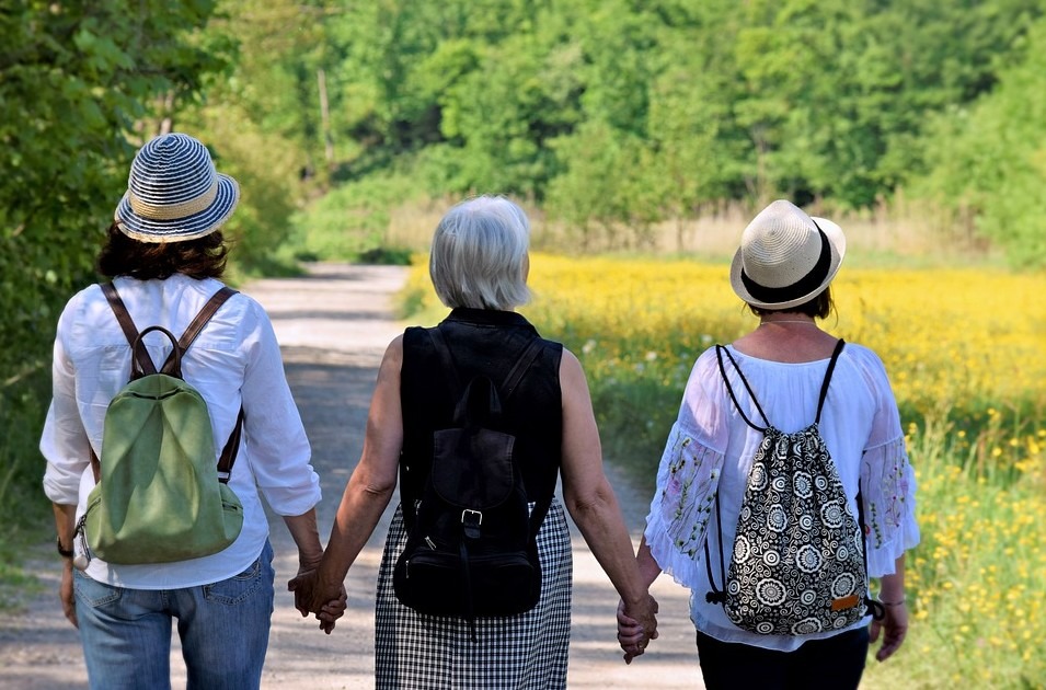 three women friends wearing backpacks and holding hands