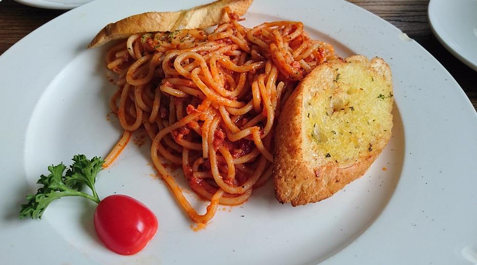 a plate of spaghetti with two pieces of garlic bread