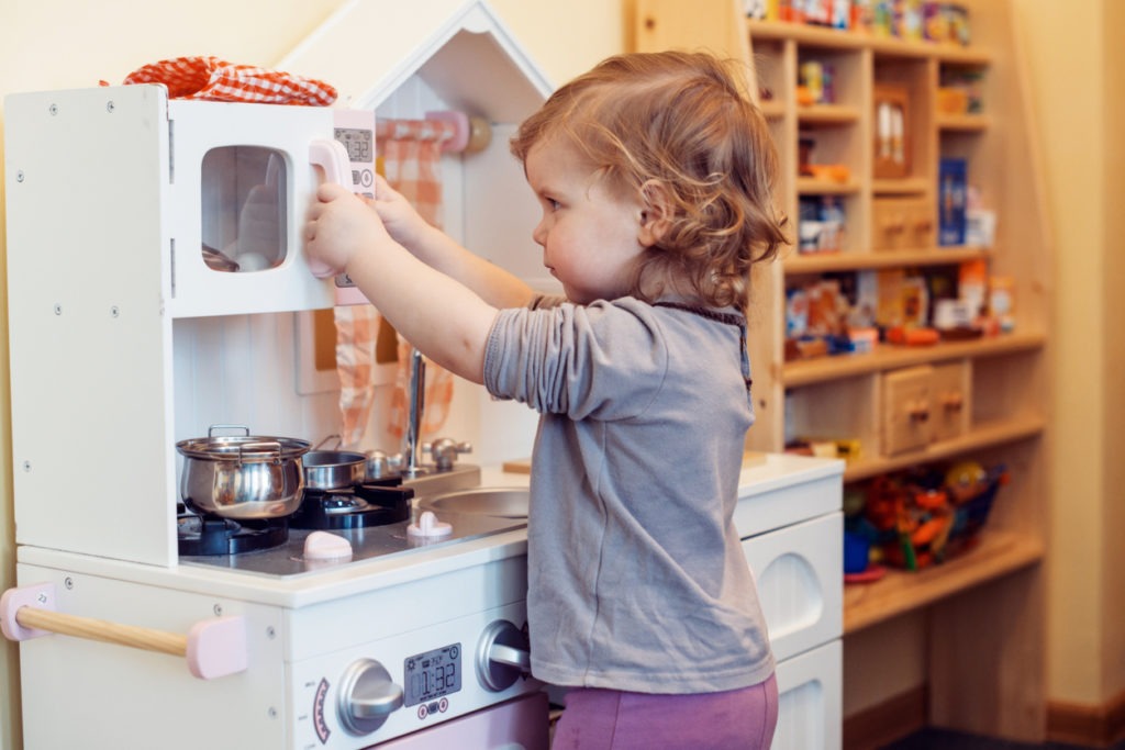 A child playing with a fake kitchen