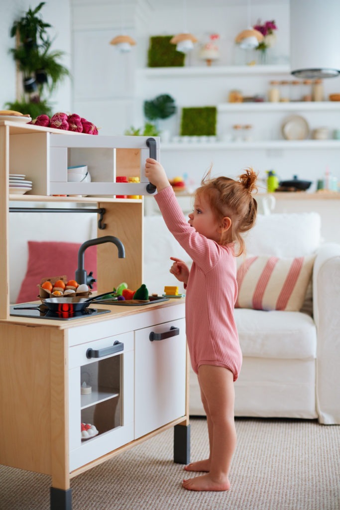 Cute toddler baby girl playing on toy kitchen