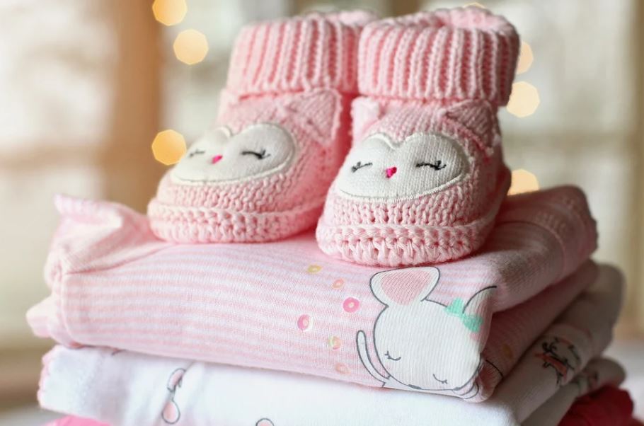 baby girl pink booties and folded clothes