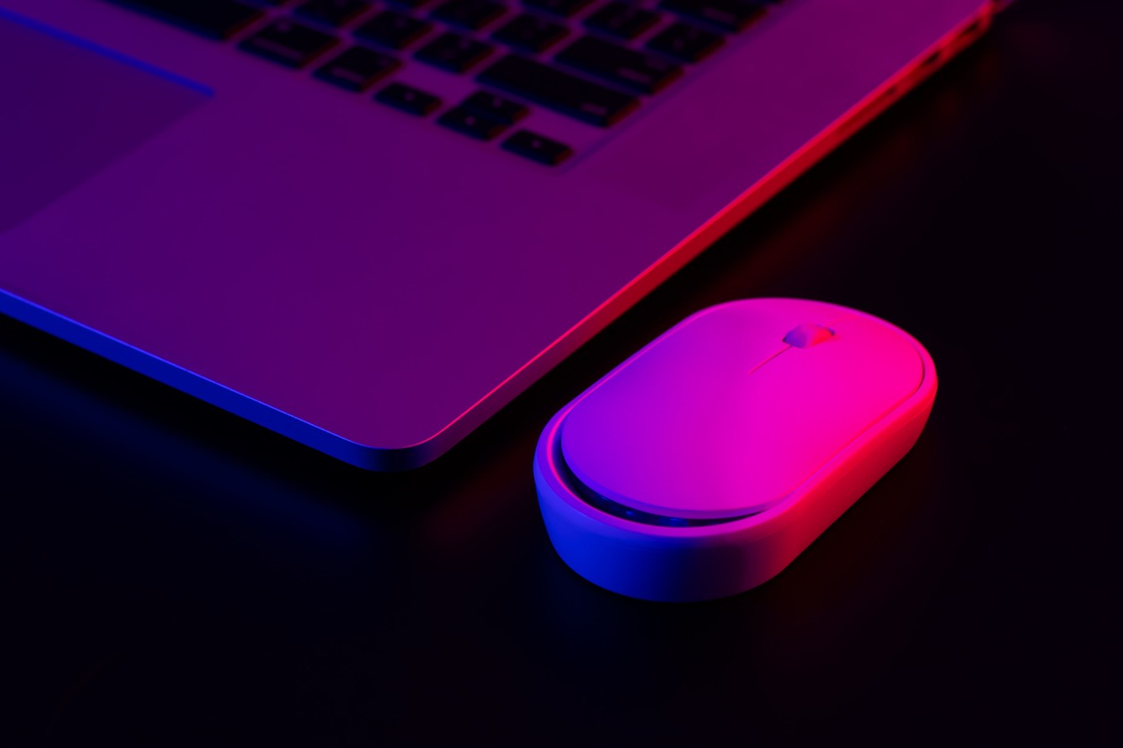 A laptop and mouse in blue and purple lighting