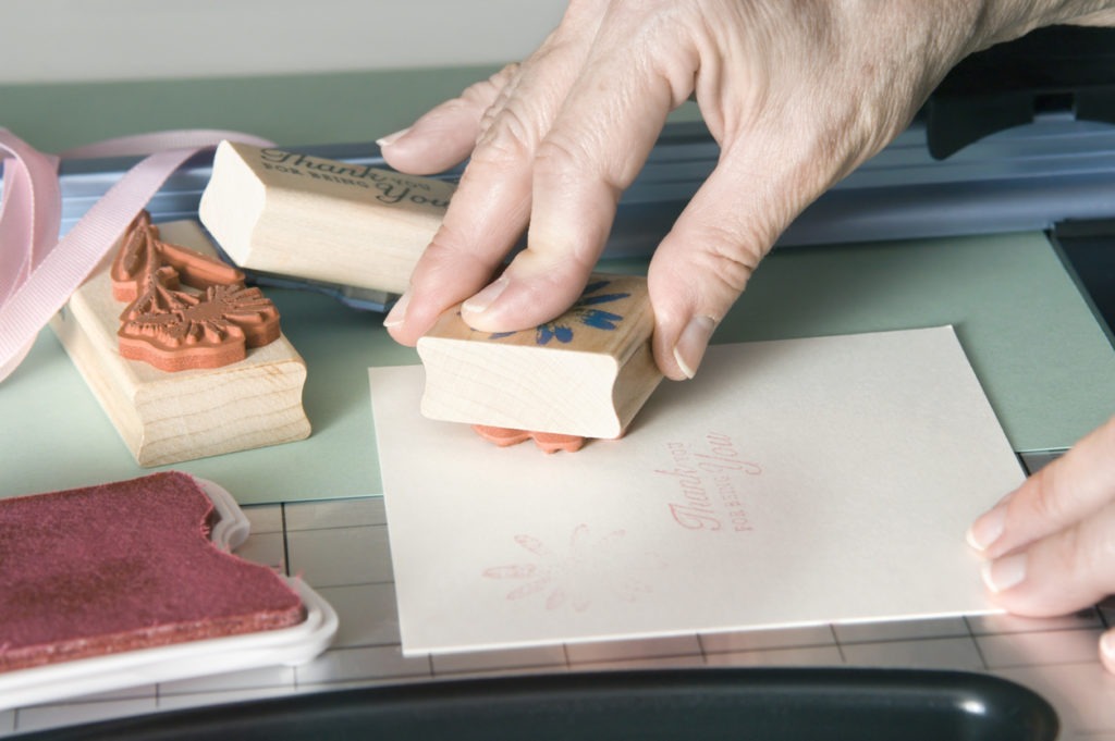 Closeup of a senior woman making homemade greeting cards with stamps and cardstock