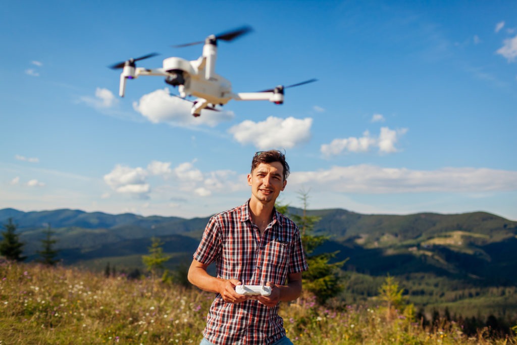 Drone remote control. Man operating copter controller in mountains. Aerial video shooting of summer Carpathians. Traveler uses new devices