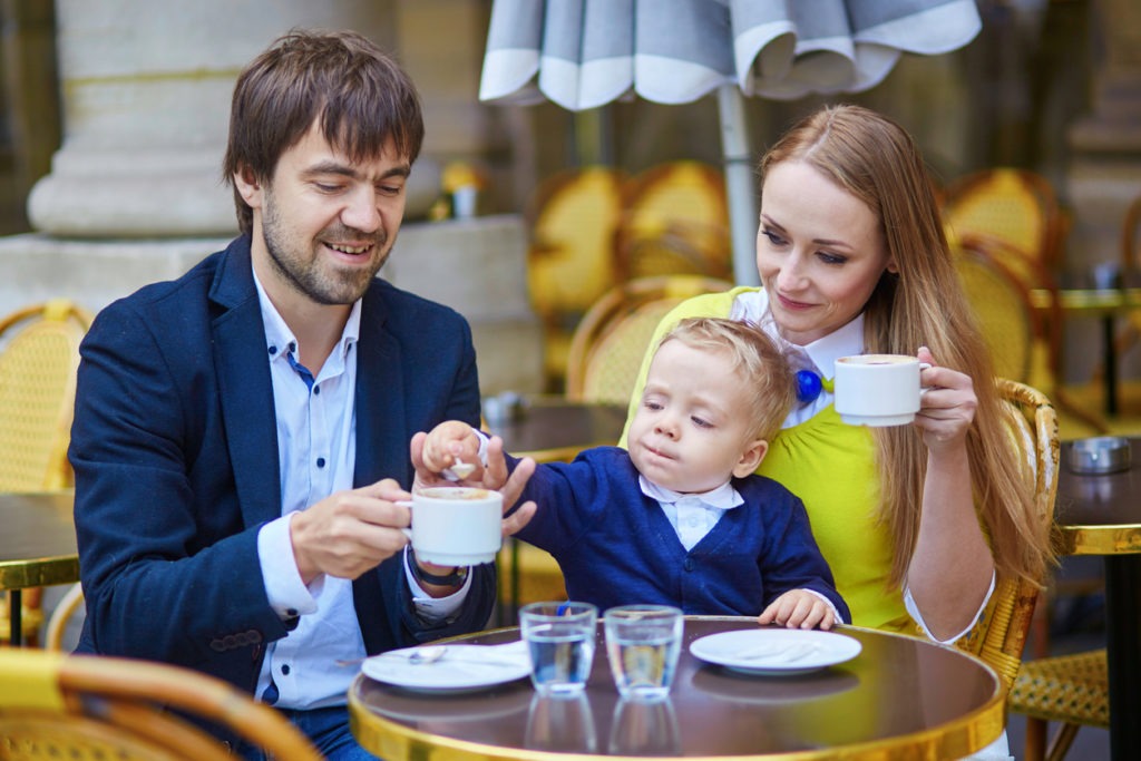 Young married couple relaxing in a coffee shop with their baby.