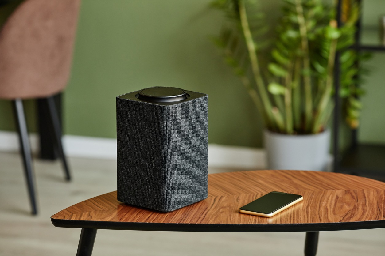 A smart speaker with home AI system on wooden table against green wall