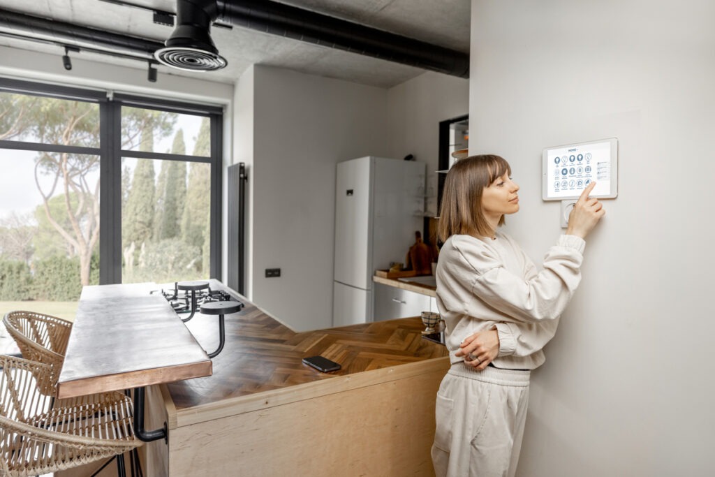 A woman controlling smart home devices with a digital tablet mounted on the wall
