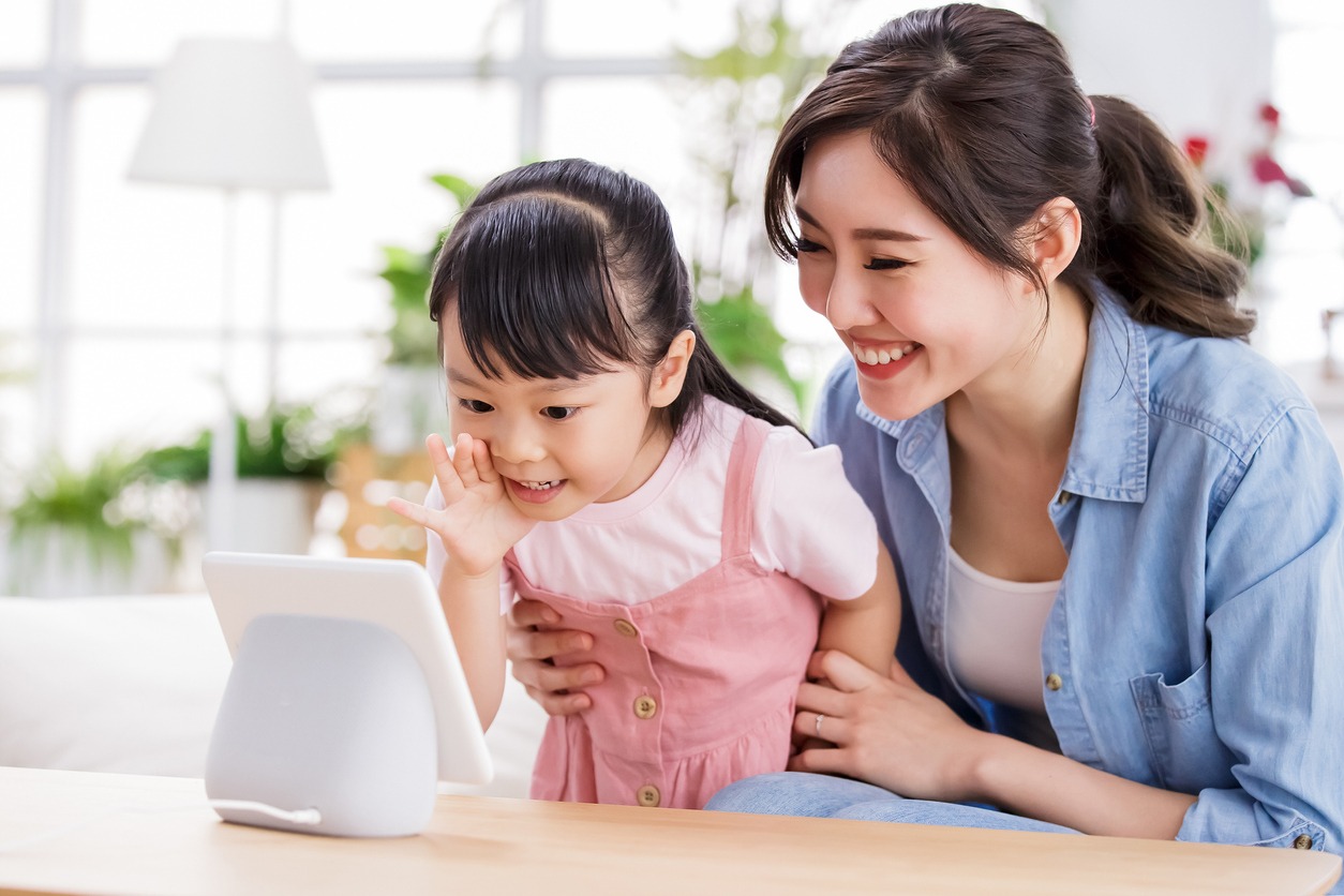 Mom and daughter talk to voice assistant with screen at home