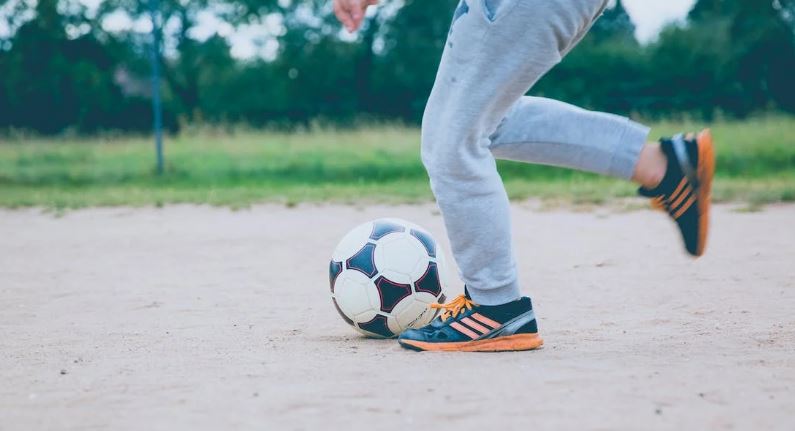 a person wearing football casual trainers about to kick the football