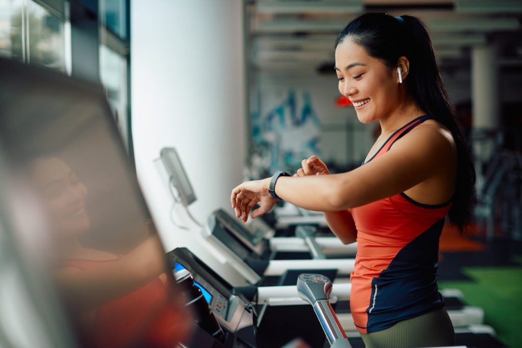 Athletic woman using fitness tracker while on a treadmill