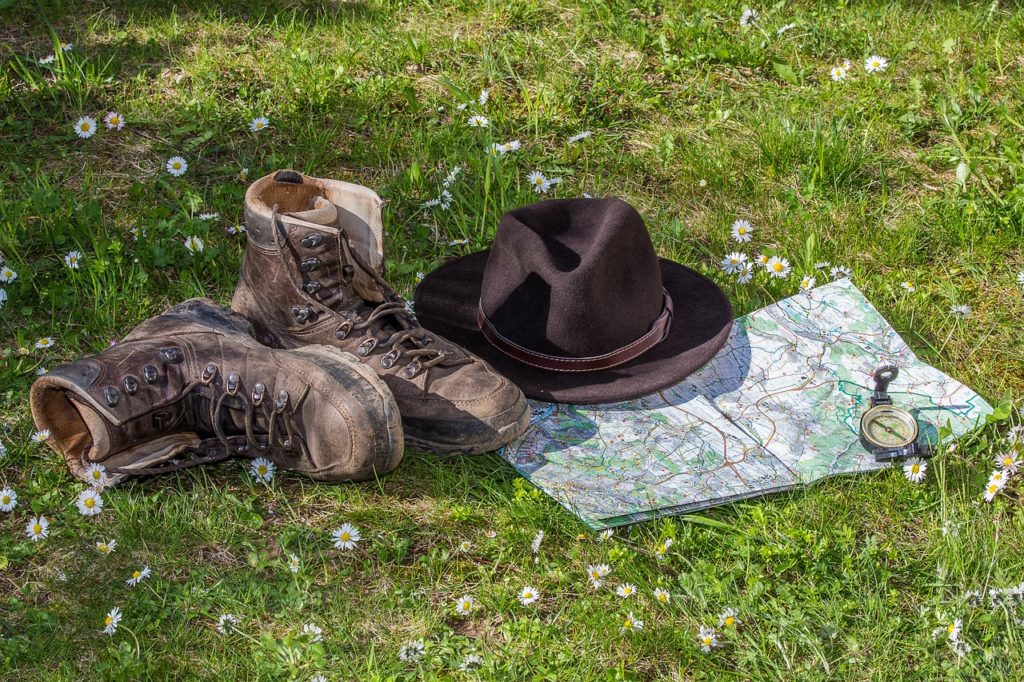 Boots-hat-map-and-compass-on-flower-grass