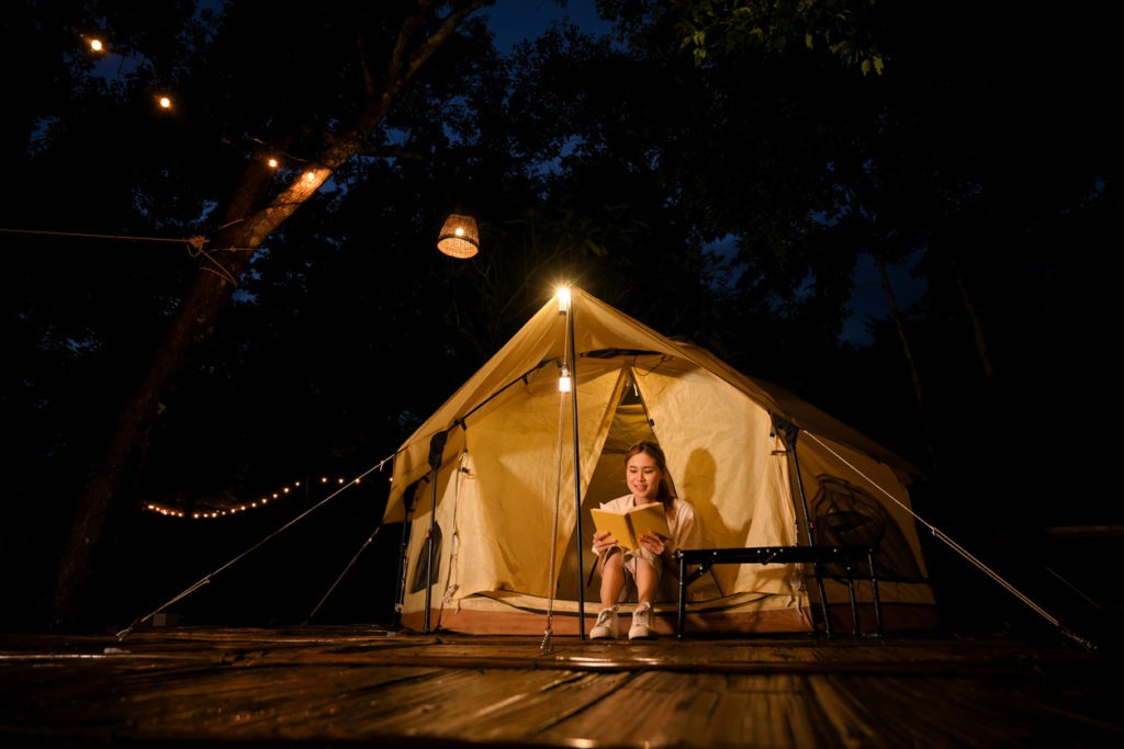 Glowing tent with fairy lights and a table with a lamp and sweet dinner set-up