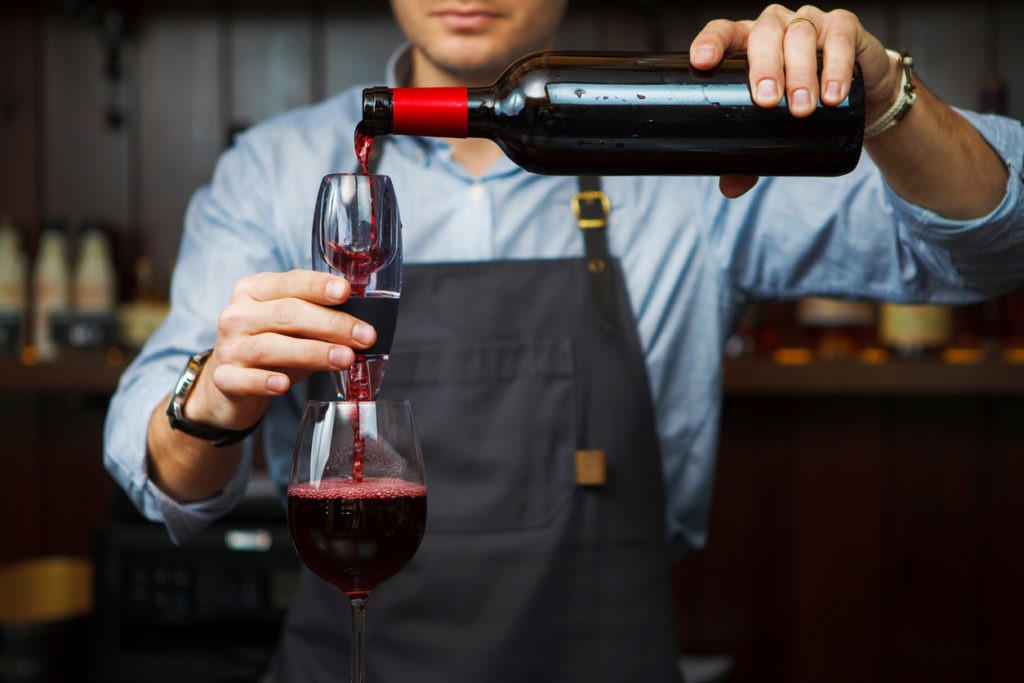 Male sommelier pouring red wine through the aerator into a glass. Aerators bring flavor-enhancing oxygen into a drink, enhancing the flavor