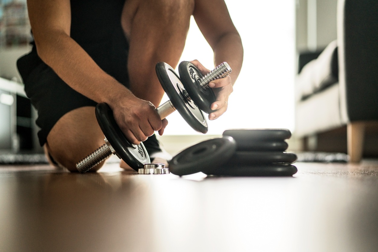 Man adding weights to his adjustable dumbbells
